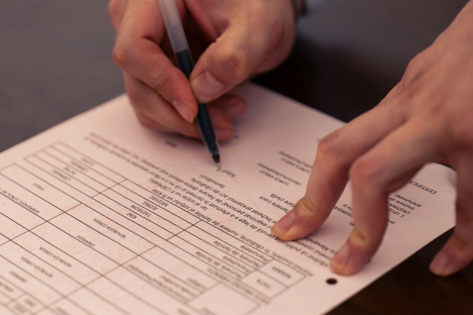 Hands holding a pen and signing a form.