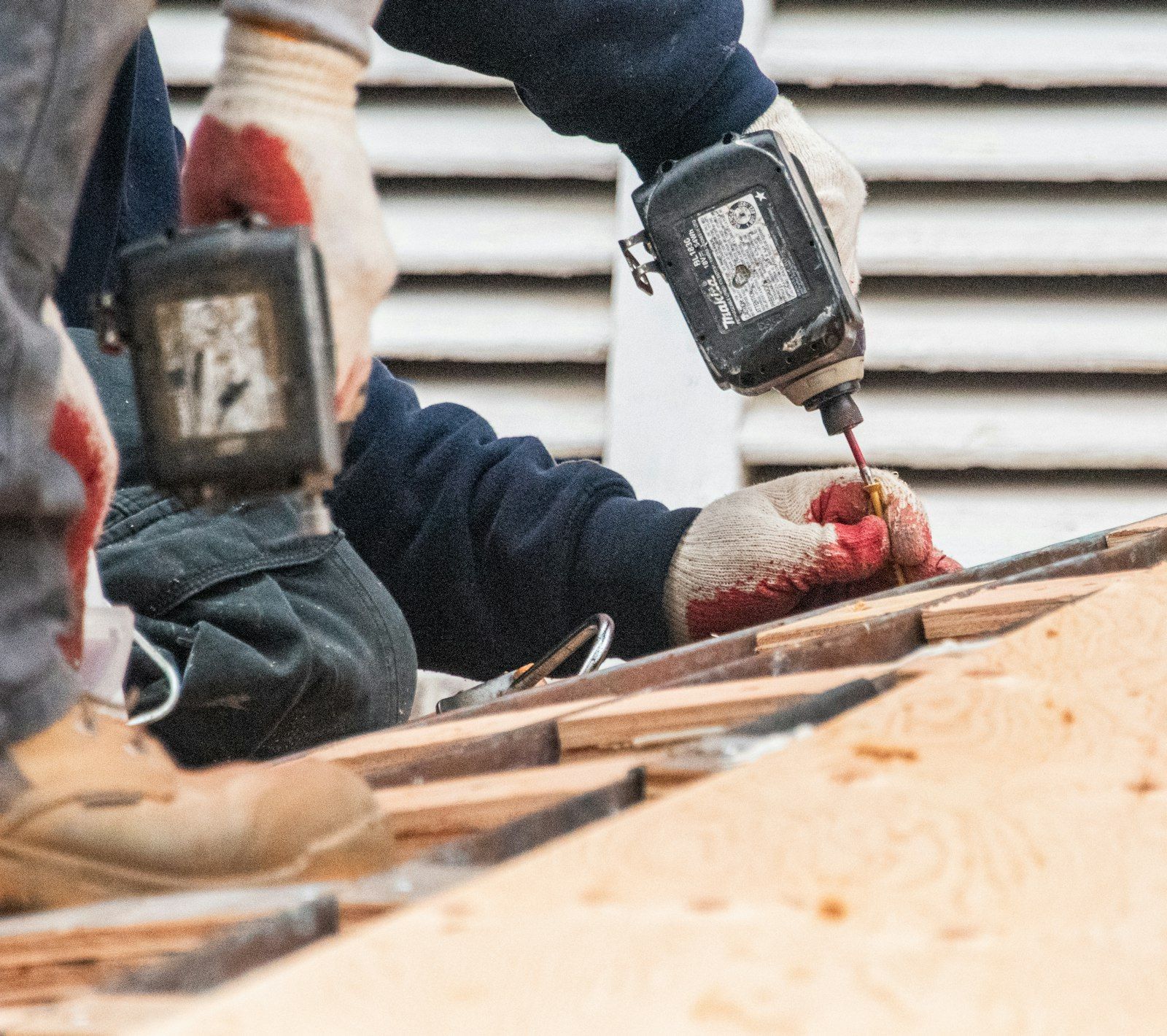 Construction workers using power drills on a roof.
