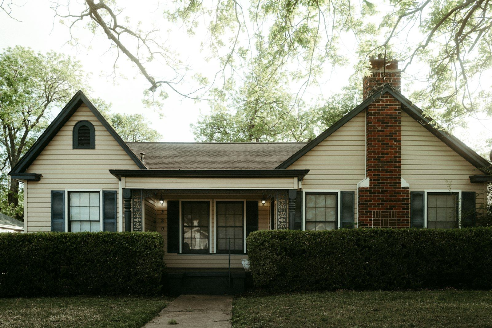 Single-story house with a tall brick chimney, shingle roof and covered front porch in Waco, Texas
