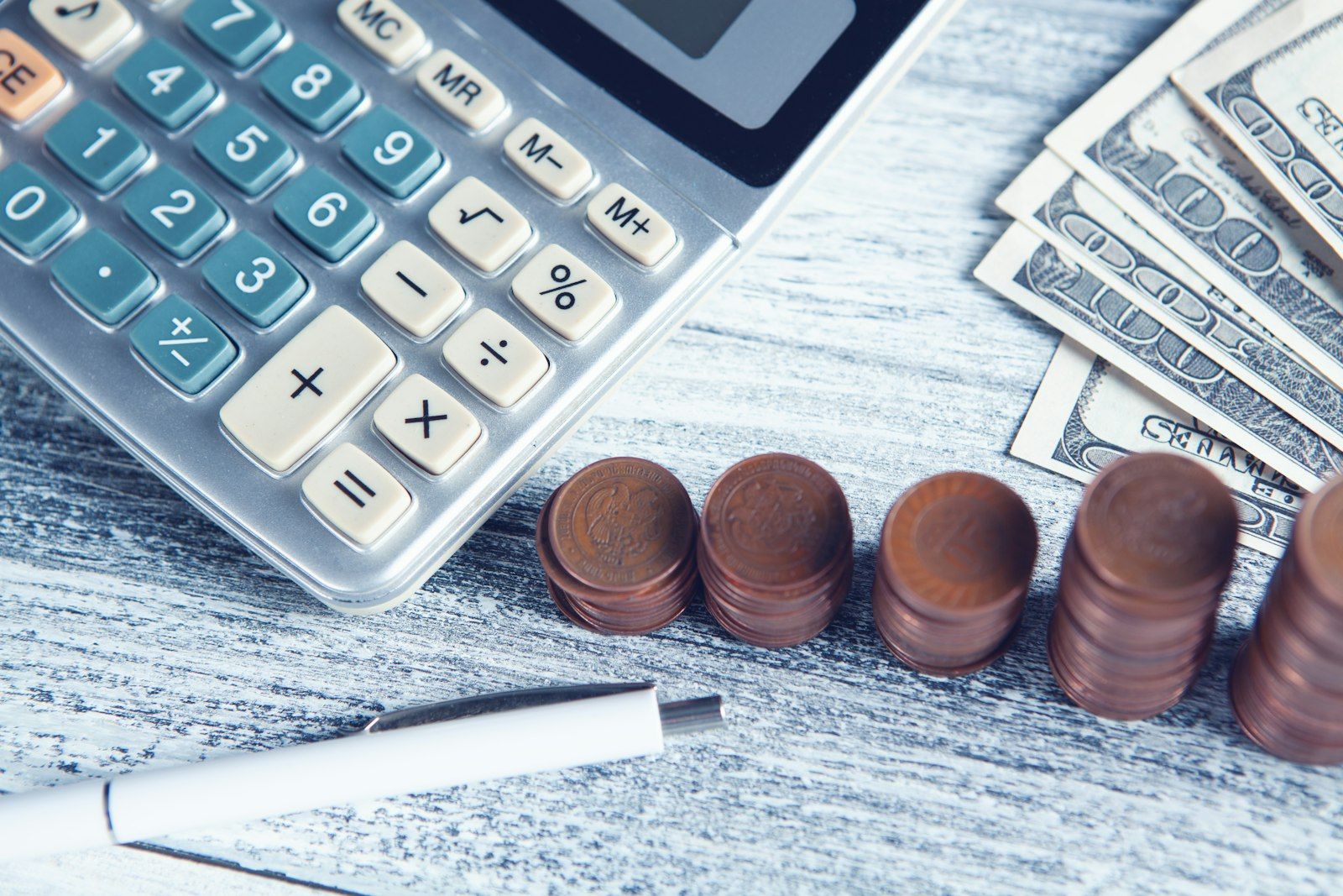 Calculator, pen and money on a table.