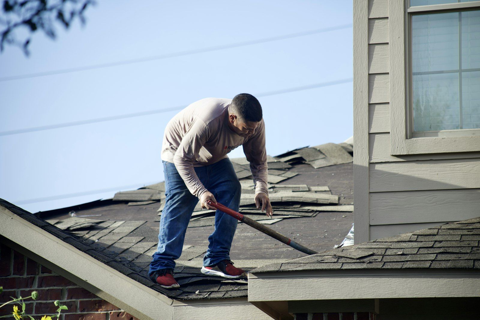 Roofer removing shingles from a residential roof.