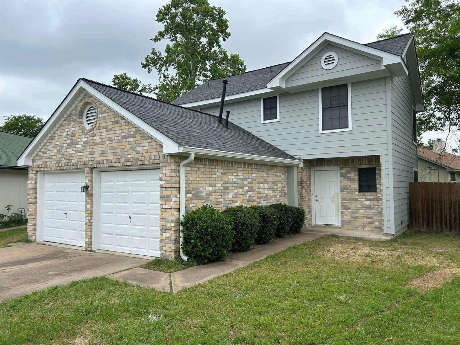 Two-story brick and siding house with white gutters, a downspout and a dark gray shingle roof